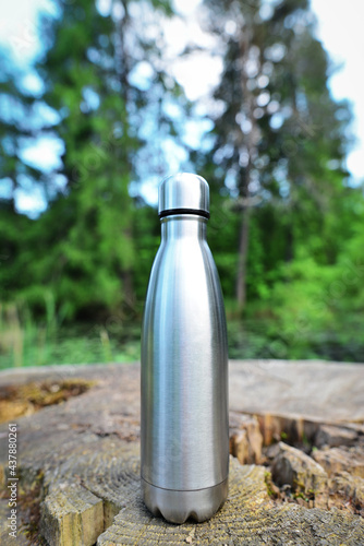 Reusable water bottle. Stainless steel reusable water bottle. Close-up of steel eco thermo water bottle on the background of the lake in the mountains. Copy space. Zero waste, no plastic. photo