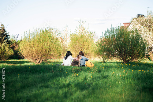 friends with a dog sit on the lawn