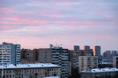 pink clouds in blue sky over urban houses at dusk