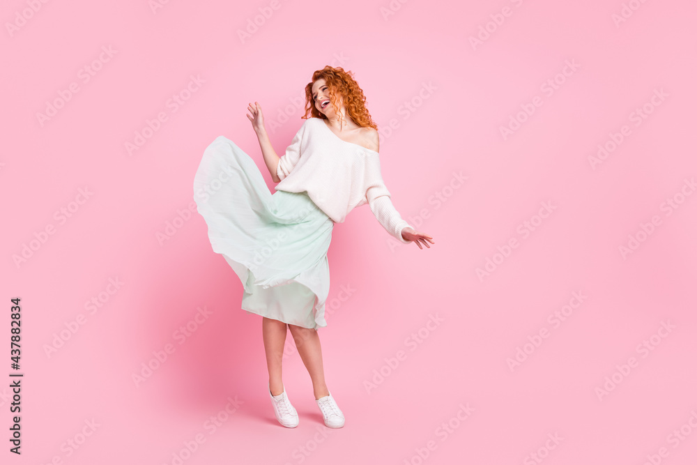 Full length body size photo of red hair woman smiling in spring skirt happy dancing at party isolated on pastel pink color background Full length body size photo of red hair woman smiling in spring skirt happy dancing at party isolated on pastel pink color background