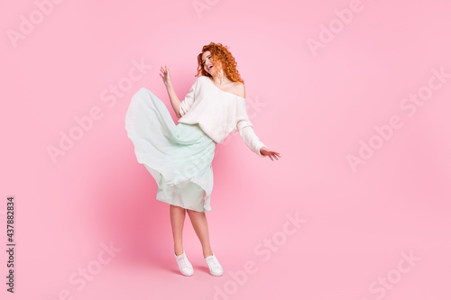 Full length body size photo of red hair woman smiling in spring skirt happy dancing at party isolated on pastel pink color background