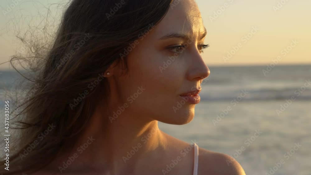 Portrait of a young slim long haired young woman stands on the shore along the ocean. Pacific Ocean. Sunset. Portrait of a young slim long haired young woman stands on the shore along the ocean. Pacific Ocean. Sunset.