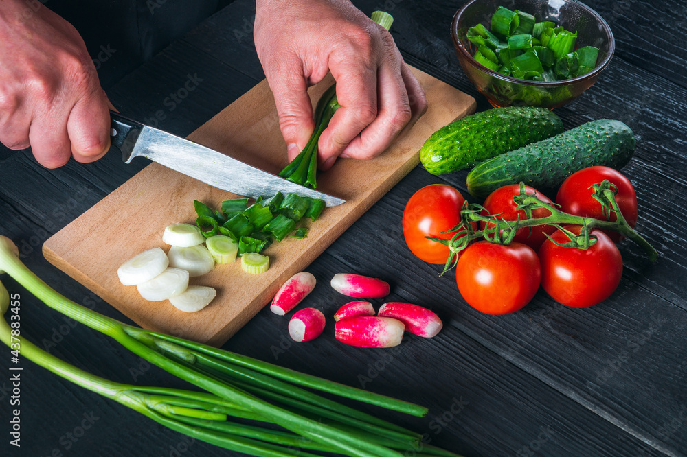 Chef hands close-up cuts young green onions. Cooking salad in the restaurant kitchen. Set of vegetables for a salad diet Chef hands close-up cuts young green onions. Cooking salad in the restaurant kitchen. Set of vegetables for a salad diet