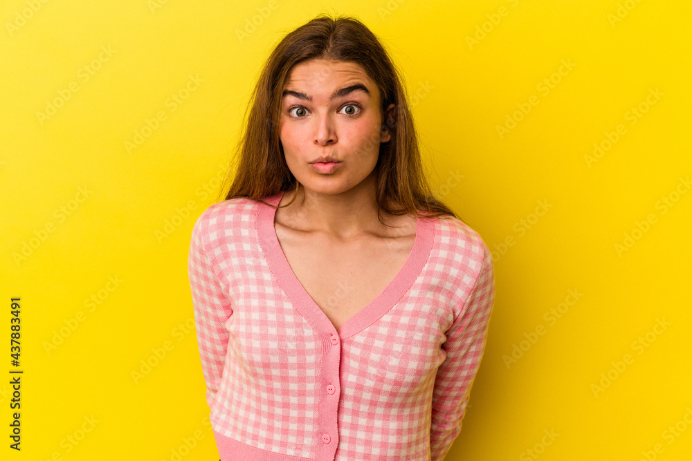 Young caucasian woman isolated on yellow background shrugs shoulders and open eyes confused. Young caucasian woman isolated on yellow background shrugs shoulders and open eyes confused.