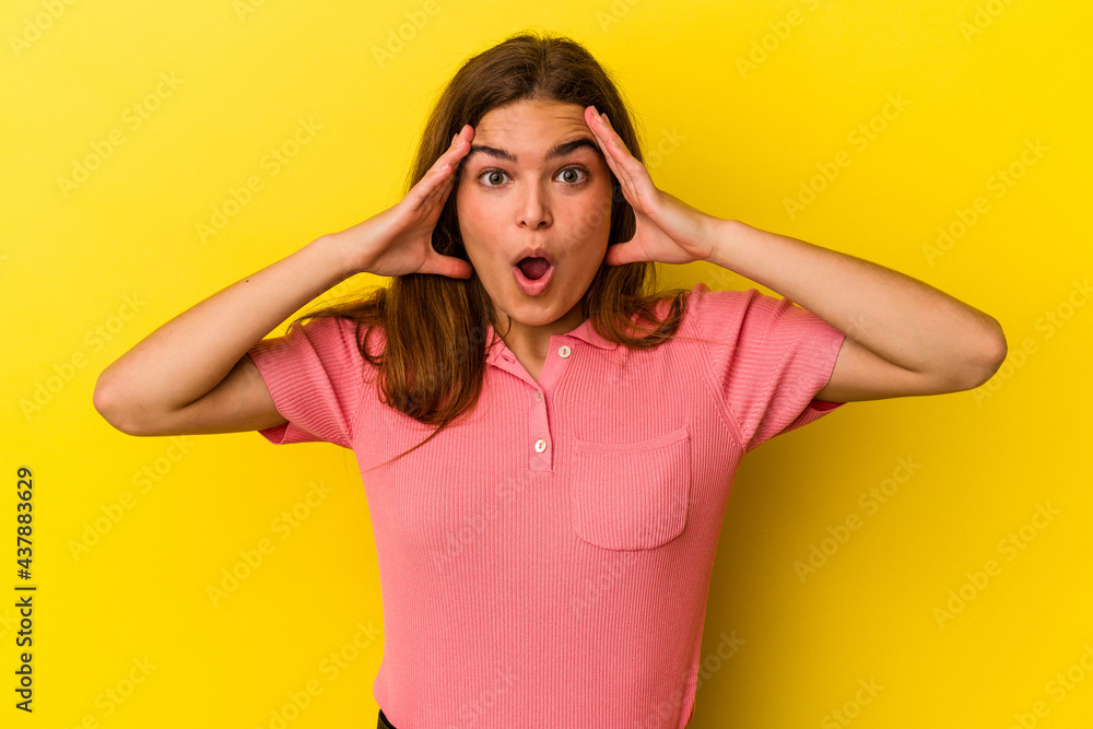 Young caucasian woman isolated on yellow background having fun covering half of face with palm. Young caucasian woman isolated on yellow background having fun covering half of face with palm.