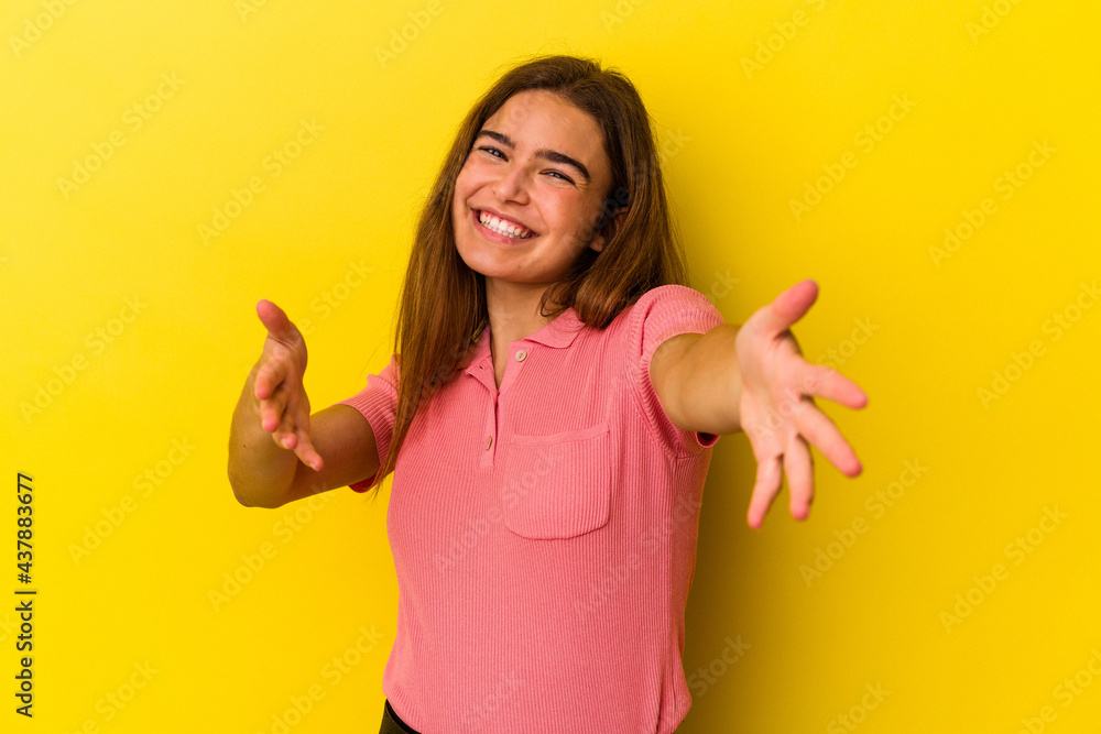 Young caucasian woman isolated on yellow background feels confident giving a hug to the camera. Young caucasian woman isolated on yellow background feels confident giving a hug to the camera.