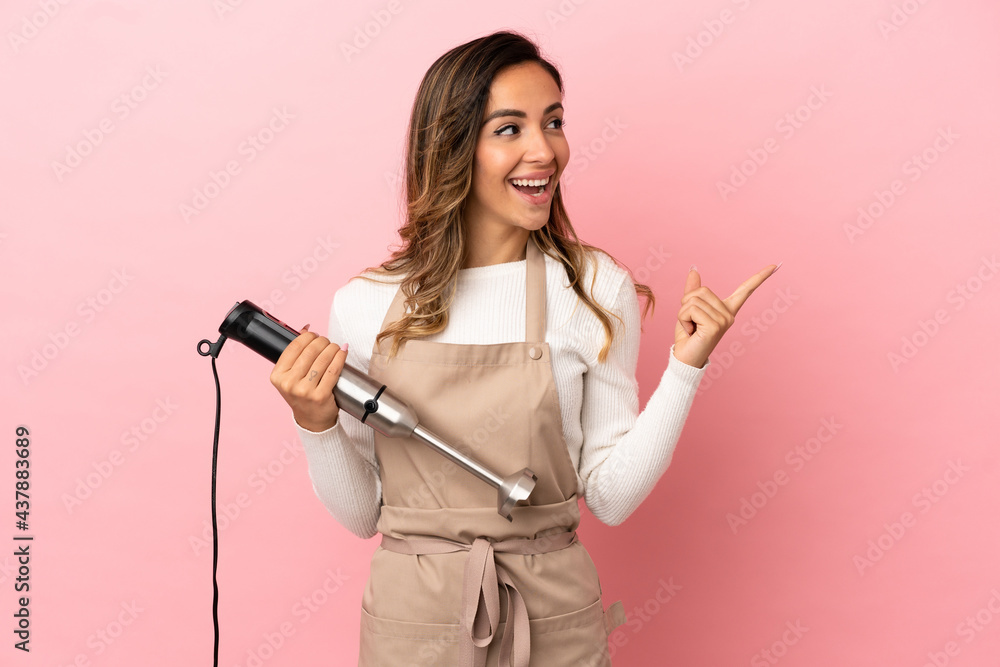 Young woman using hand blender over isolated pink background intending to realizes the solution while lifting a finger up Young woman using hand blender over isolated pink background intending to realizes the solution while lifting a finger up