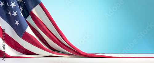 United States of America flag on white table on blue sky background. Celebration of the Fourth of July or US Independence Day backdrop