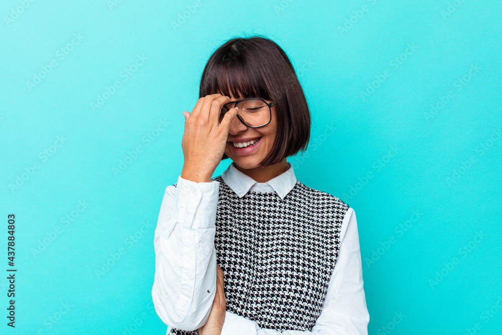 Young mixed race woman isolated on blue background blink at the camera through fingers, embarrassed covering face. Young mixed race woman isolated on blue background blink at the camera through fingers, embarrassed covering face.