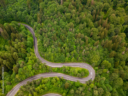Aerial view of winding road in high mountain pass trough dense green pine woods.