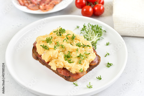 Scrambled eggs with microgreen and bacon on bread