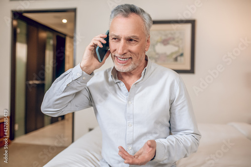 Tableau sur toile Mid-aged gray-haired businessman talking on the phone and looking involved