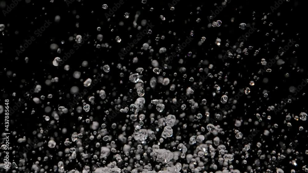 Multiple drops of water fly up and spray in different directions on black background. Macro shot of transparent liquid creating droplets and splashes caused by sound vibrations. Slow motion. Close up. Multiple drops of water fly up and spray in different directions on black background. Macro shot of transparent liquid creating droplets and splashes caused by sound vibrations. Slow motion. Close up.