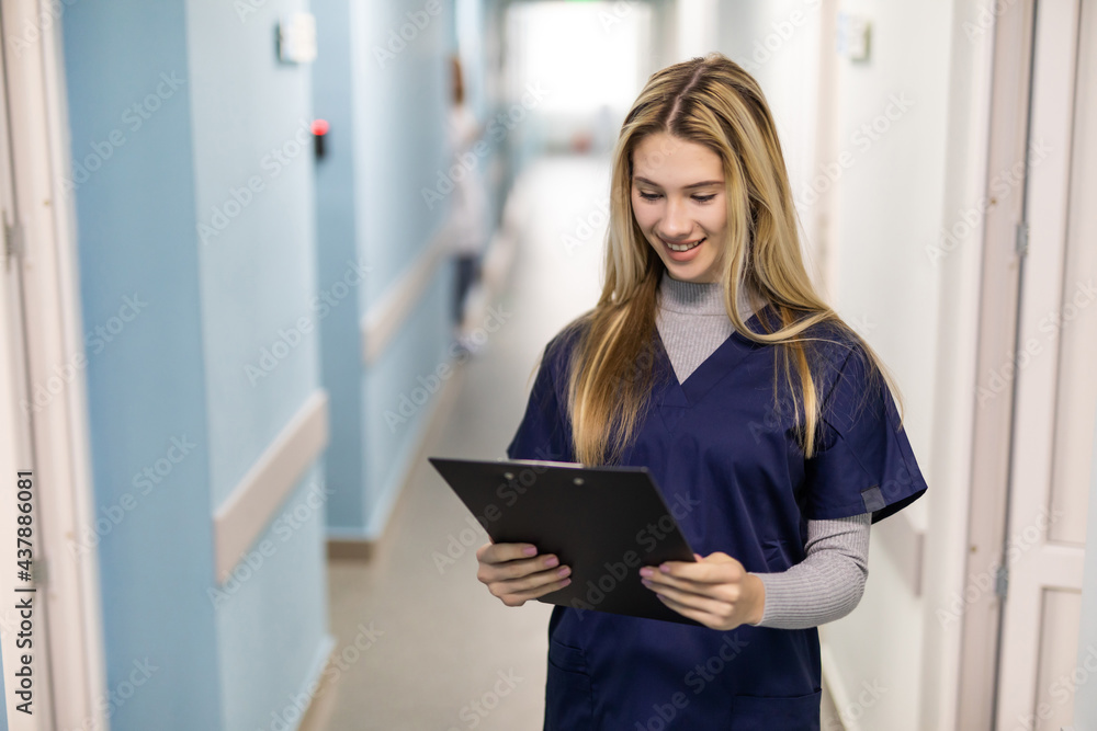 Portrait of mature female nurse working in hospital. Woman healthcare worker with clipboard in corridor. Portrait of mature female nurse working in hospital. Woman healthcare worker with clipboard in corridor.