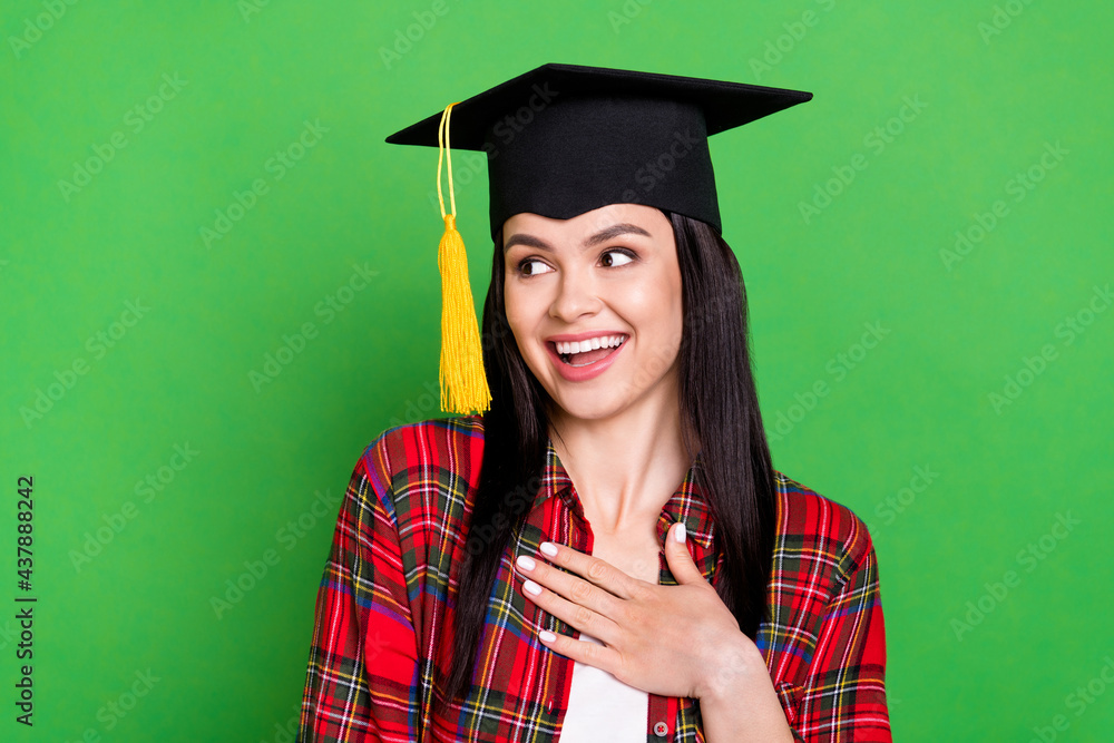 Photo of brunette impressed young lady celebrating look empty space wearing graduate cap red shirt isolated on green color background Photo of brunette impressed young lady celebrating look empty space wearing graduate cap red shirt isolated on green color background