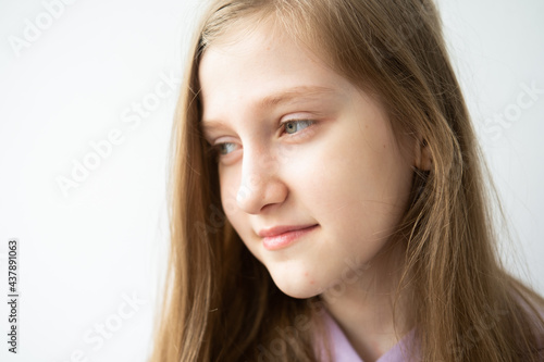 portrait of beautiful teenage girl with long hair in purple hoodie standing against white wall