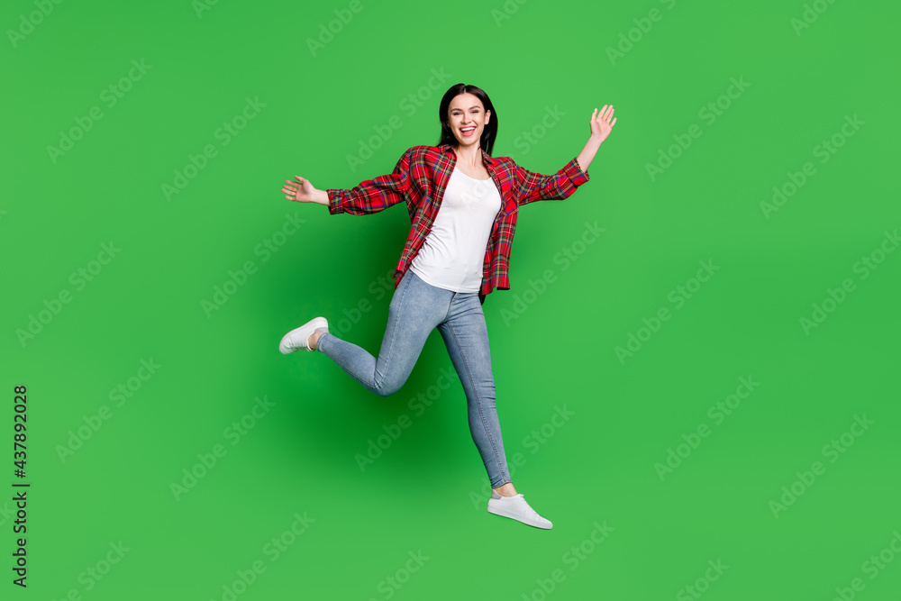 Full body profile photo of brunette astonished young lady jump wear shirt jeans isolated on green color background Full body profile photo of brunette astonished young lady jump wear shirt jeans isolated on green color background