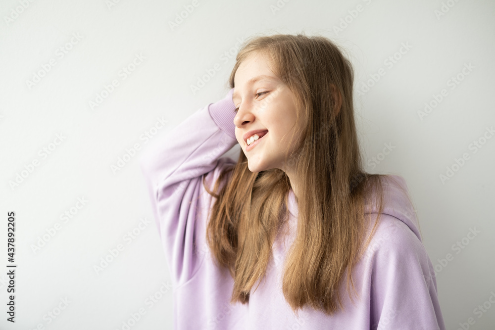 beautiful teenage girl with long hair in purple hoodie standing against white wall beautiful teenage girl with long hair in purple hoodie standing against white wall