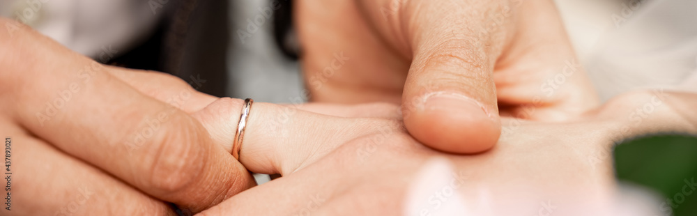 partial view of man putting wedding ring on finger of bride, banner