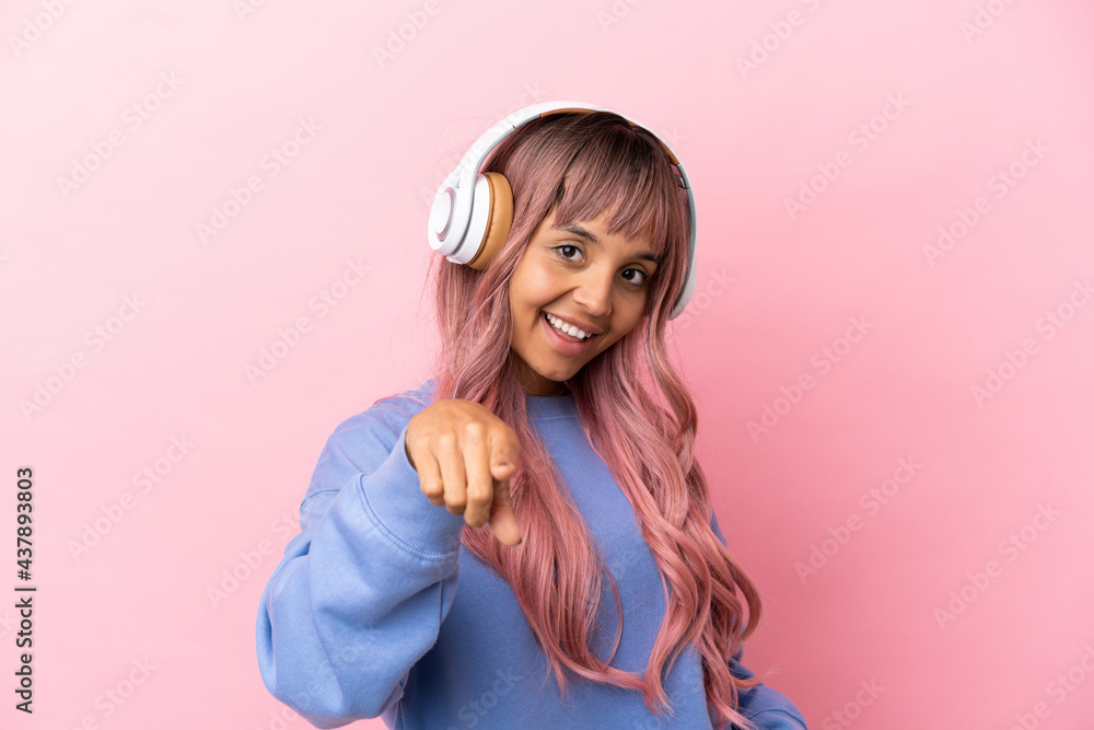 Young mixed race woman with pink hair isolated on pink background listening music Young mixed race woman with pink hair isolated on pink background listening music