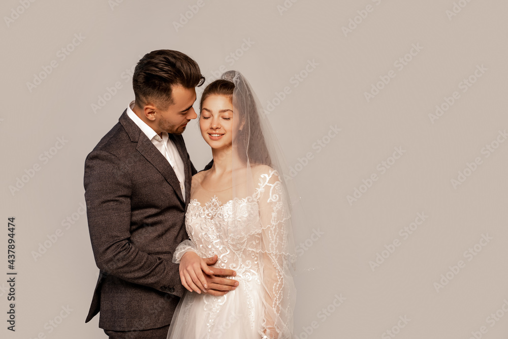 young groom near smiling elegant bride isolated on grey with lilac shadow