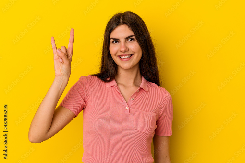 Young caucasian woman isolated on yellow background showing a horns gesture as a revolution concept. Young caucasian woman isolated on yellow background showing a horns gesture as a revolution concept.