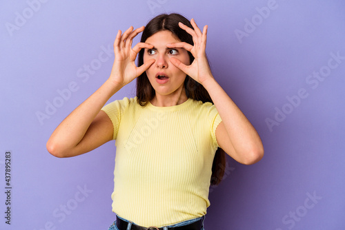 Young caucasian woman isolated on purple background keeping eyes opened to find a success opportunity.