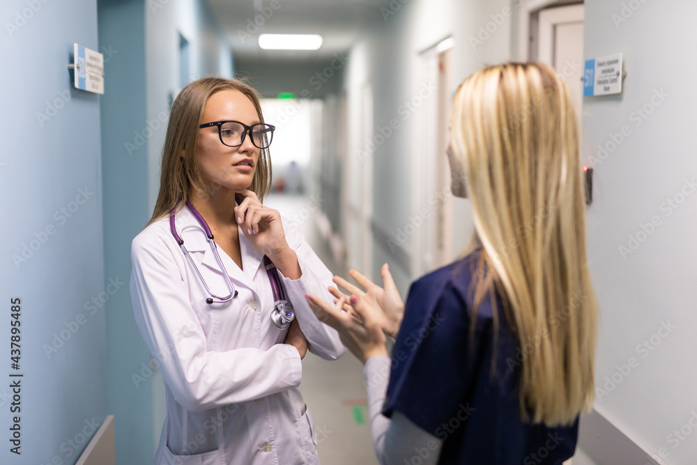 Two woman doctor with mask talking in hospital corridor, health care. female doctors examining a file in a bright office. Two woman doctor with mask talking in hospital corridor, health care. female doctors examining a file in a bright office.