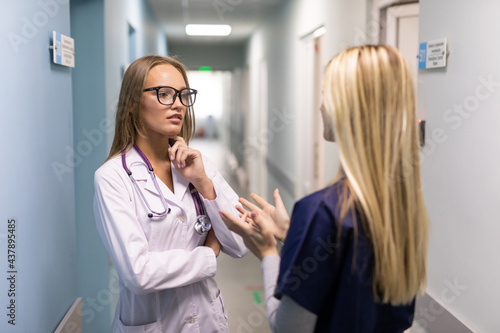 Wallpaper Mural Two woman doctor with mask talking in hospital corridor, health care. female doctors examining a file in a bright office. Torontodigital.ca