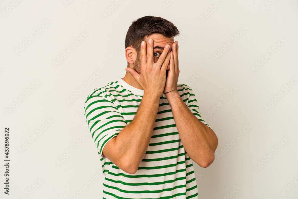 Young caucasian man isolated on white background blink through fingers frightened and nervous. Young caucasian man isolated on white background blink through fingers frightened and nervous.