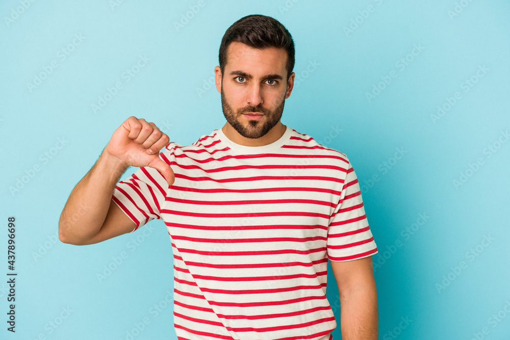 Young caucasian man isolated on blue background showing a dislike gesture, thumbs down. Disagreement concept. Young caucasian man isolated on blue background showing a dislike gesture, thumbs down. Disagreement concept.
