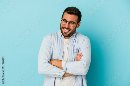 Young caucasian man isolated on blue background funny and friendly sticking out tongue. © Asier