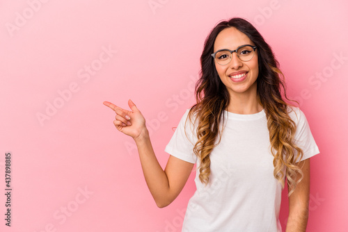 Young mexican woman isolated on pink background smiling cheerfully pointing with forefinger away. © Asier