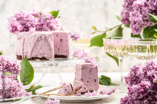 Delicious dessert blueberry tart with fresh berries, sweet tasty mousse cake, berry pie. French cuisine, with a bouquet of purple blooming lilacs