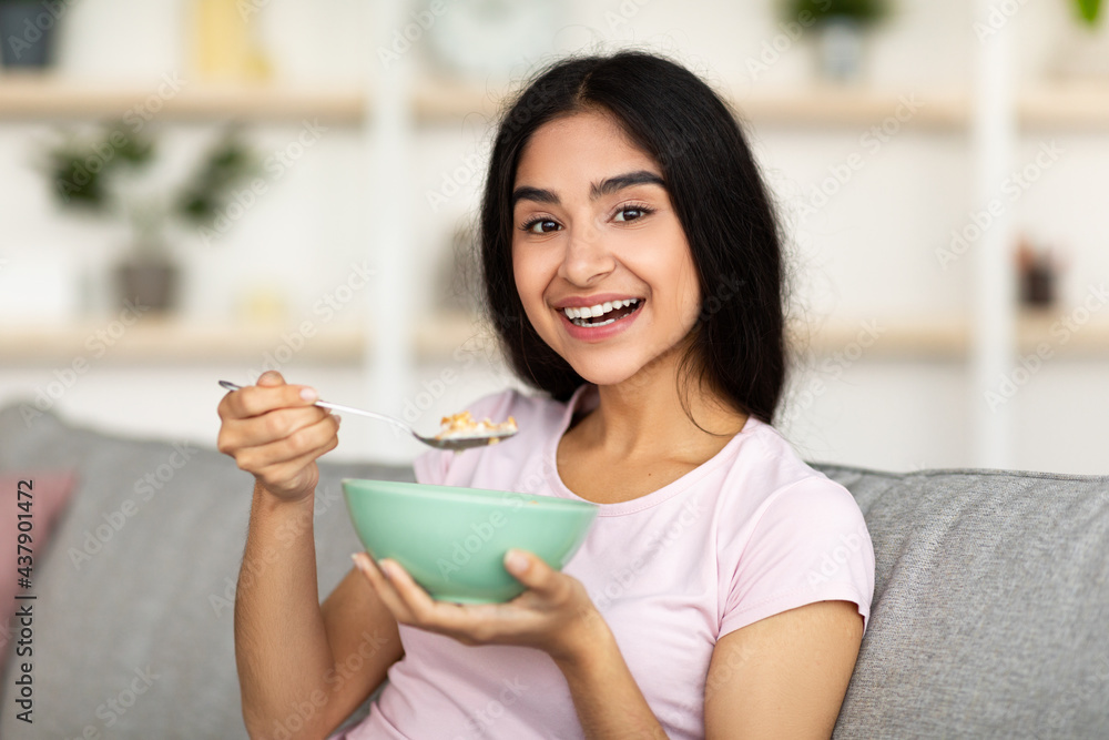 Healthy diet, weight loss concept. Smiling Indian lady eating cereal, having nutritious breakfast at home Healthy diet, weight loss concept. Smiling Indian lady eating cereal, having nutritious breakfast at home