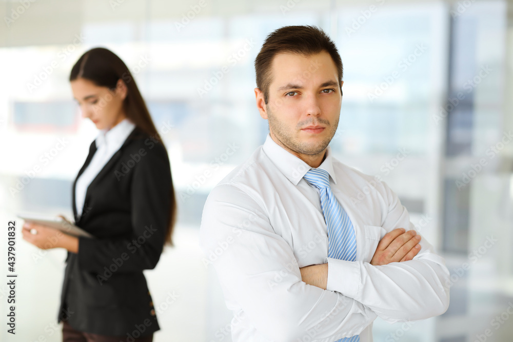 Portrait of a self-confident middle-aged businessman, standing with his colleague in the background in a modern office. Business concept Portrait of a self-confident middle-aged businessman, standing with his colleague in the background in a modern office. Business concept