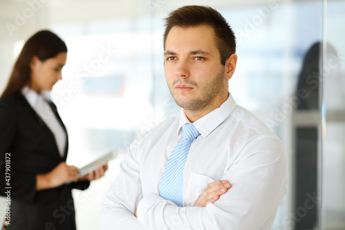 Portrait of a self-confident middle-aged businessman, standing with his colleague in the background in a modern office. Business concept