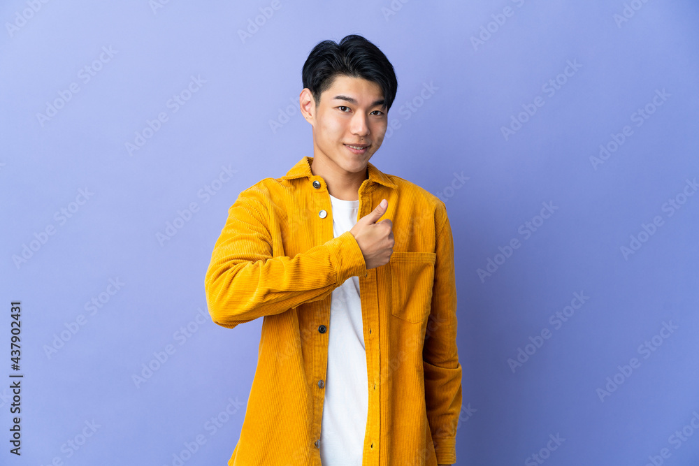 Young Chinese man isolated on purple background giving a thumbs up gesture Young Chinese man isolated on purple background giving a thumbs up gesture