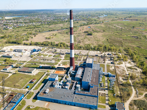 High chimney of a power plant on the outskirts of the city. Green spring steppe on the background. Aerial drone view. photo