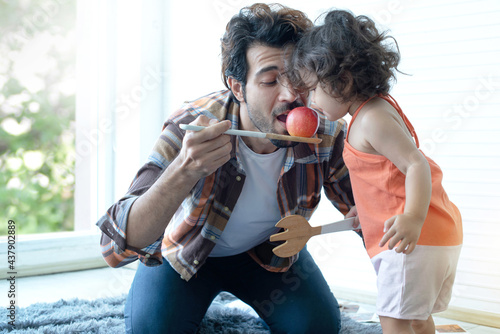 Bilde på lerret Father and little daughter with red apple, pretend eating their apple on  big wo