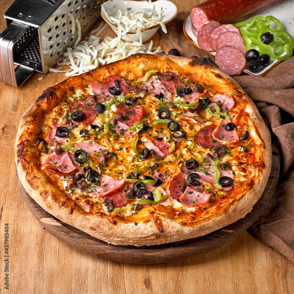 Traditional italian Pizza with salami, mozzarella, ham and bacon on wooden background.