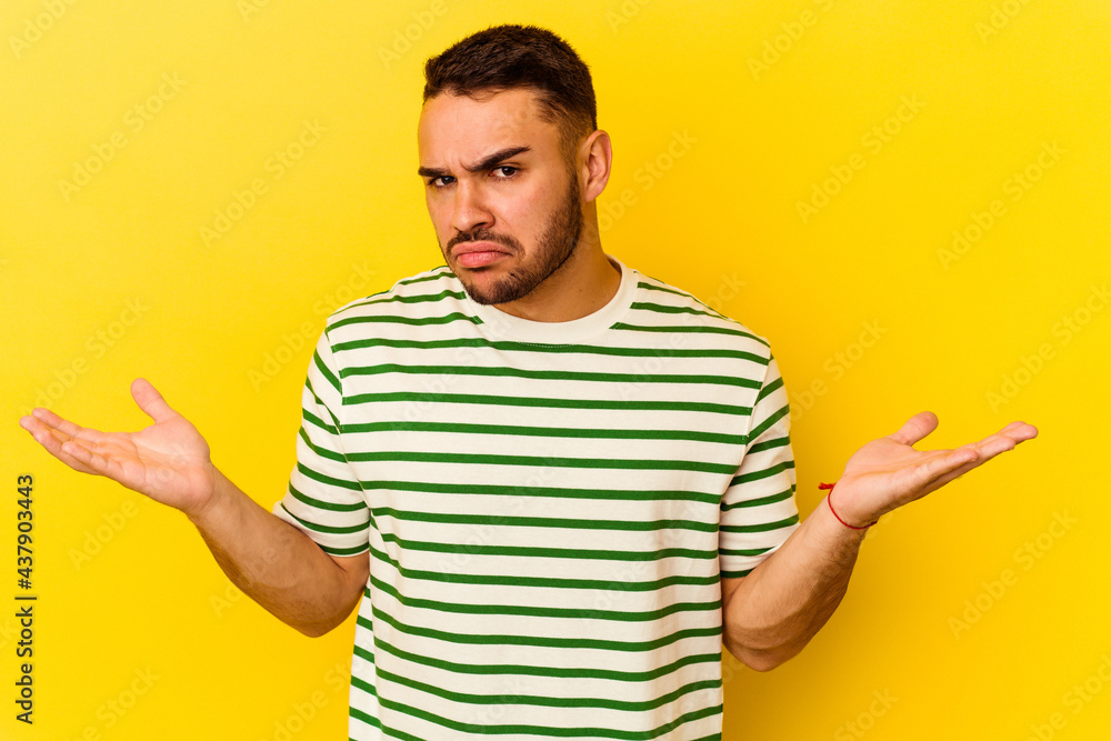 Young caucasian man isolated on yellow background doubting and shrugging shoulders in questioning gesture. Young caucasian man isolated on yellow background doubting and shrugging shoulders in questioning gesture.
