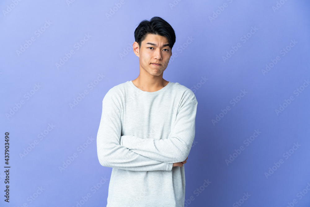 Young Chinese man isolated on purple background with unhappy expression Young Chinese man isolated on purple background with unhappy expression