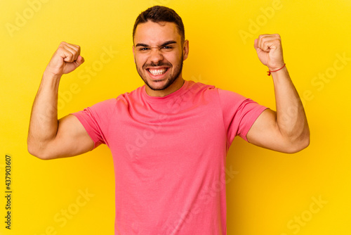 Young caucasian man isolated on yellow background showing strength gesture with arms, symbol of feminine power