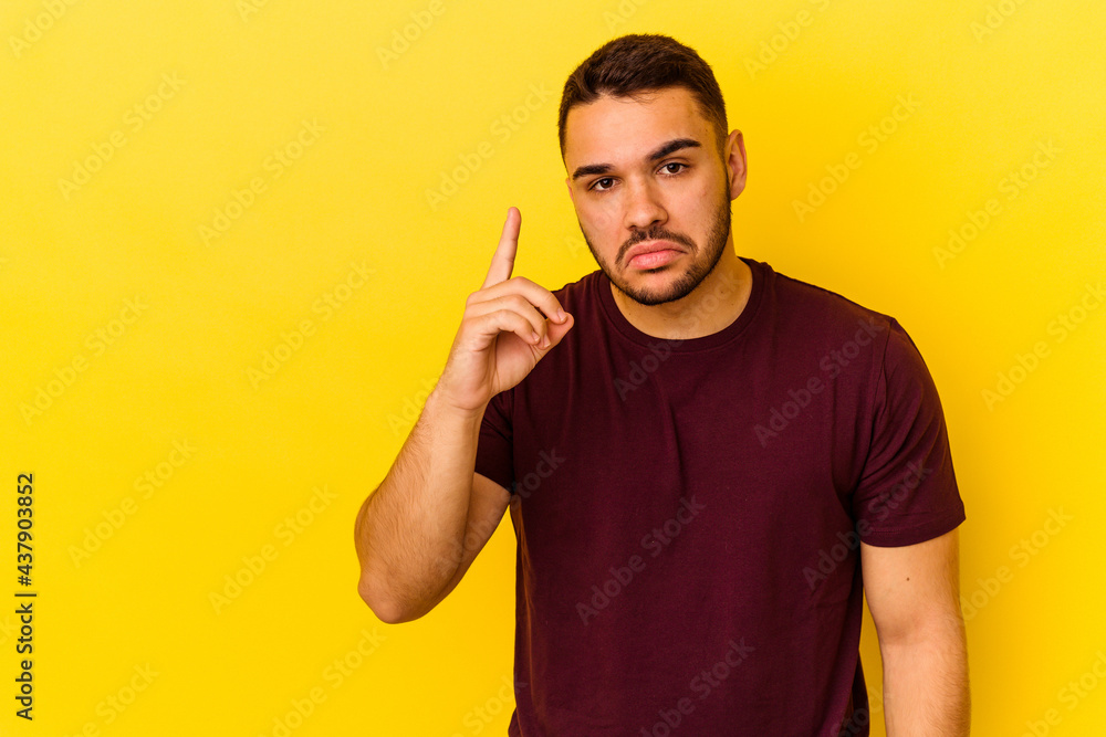 Young caucasian man isolated on yellow background showing number one with finger. Young caucasian man isolated on yellow background showing number one with finger.