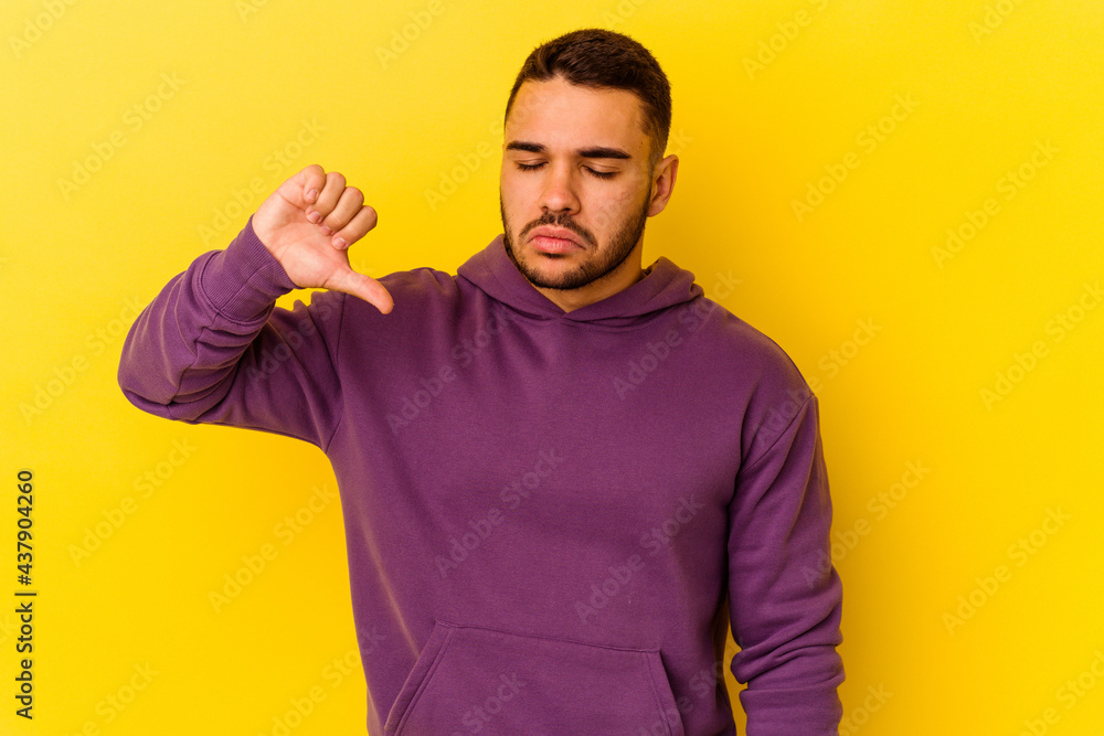 Young caucasian man isolated on yellow background showing a dislike gesture, thumbs down. Disagreement concept. Young caucasian man isolated on yellow background showing a dislike gesture, thumbs down. Disagreement concept.