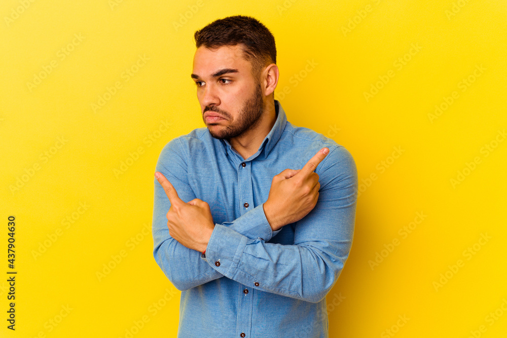 Young caucasian man isolated on yellow background points sideways, is trying to choose between two options. Young caucasian man isolated on yellow background points sideways, is trying to choose between two options.