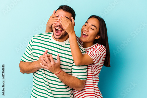 Young mixed race couple isolated on blue background