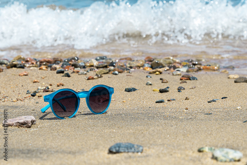 blue sunglasses on the beach on the surf background