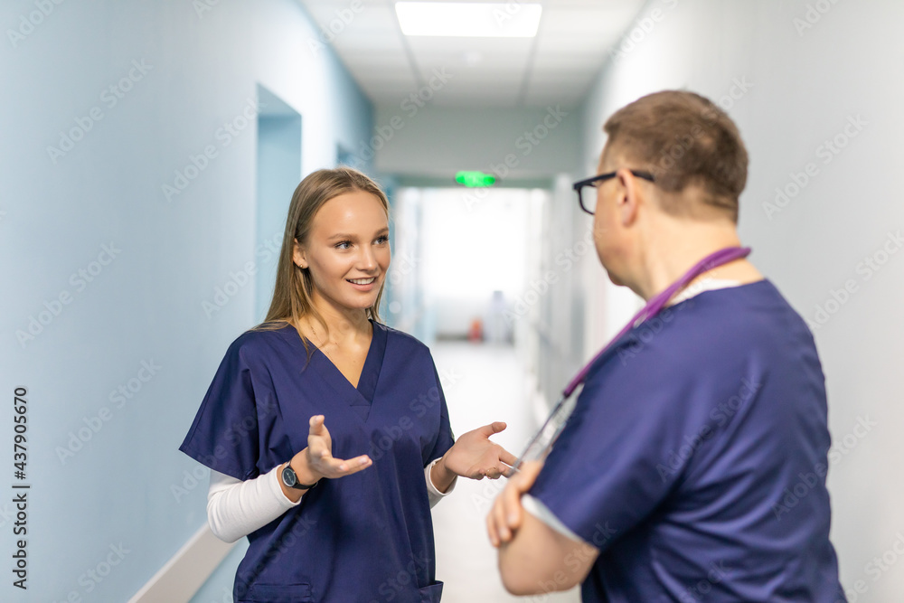 Fototapeta premium Beautiful mature doctors in white coats while standing in hospital corridor